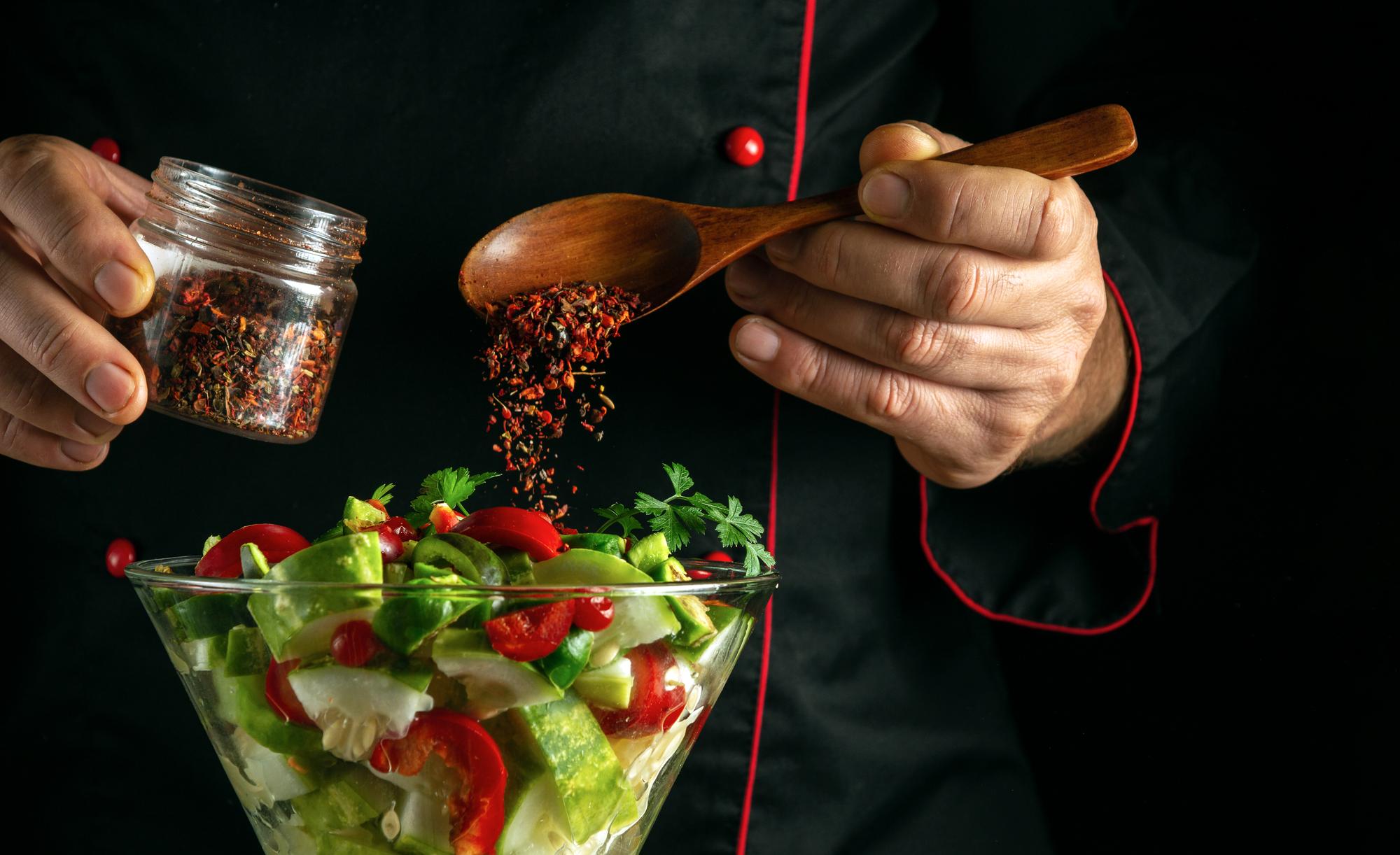 chef tasting sauce in kitchen